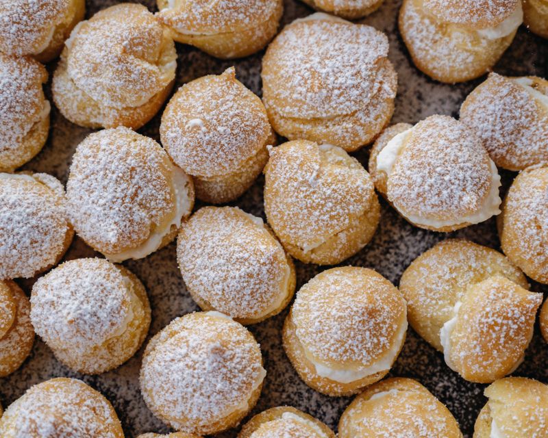 A tray of cream cheese choux puffs dusted with sugar
