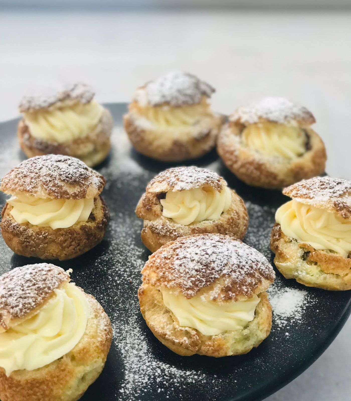 Freshly baked choux cream puffs dusted with powdered sugar